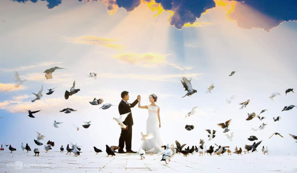 Các cặp đôi chụp ảnh cưới với đàn bồ câu. Ảnh: VnExpress.